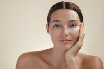 Close-up portrait of a young woman with radiant skin and a soft smile, resting her cheek on her hand. Ideal for beauty, skincare, and wellness concepts. Perfect for high-quality cosmetic promotions.