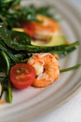 Macro shot of a shrimp salad with juicy cherry tomatoes, avocado slices, and crisp arugula leaves.