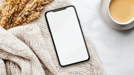A smartphone with a blank display resting on a cozy knitted blanket, creating a warm aesthetic