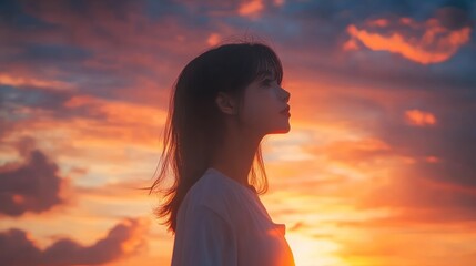 A silhouette of a woman against a vibrant sunset sky, evoking a sense of tranquility.