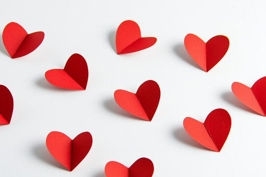 Red paper hearts on a white background. Cute romantic decor for valentine's day, wedding, birthday.