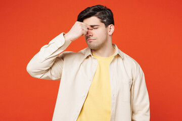 Young sad sick ill tired exhausted man wear white shirt yellow t-shirt casual clothes keep eyes closed rub put hand on nose isolated on plain red orange background studio portrait. Lifestyle concept.