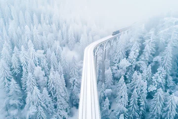 winter landscape photography, the landwasser viaduct stands majestic in snow, seen from above by a drone a train speeds gracefully across the historic bridge amid a snowy landscape