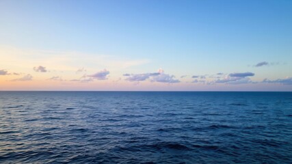 Tranquil Ocean Landscape at Dusk with Calm Water and Soft Cloud Reflections Beneath a Beautifully Colored Sky During Sunset in a Serene Environment
