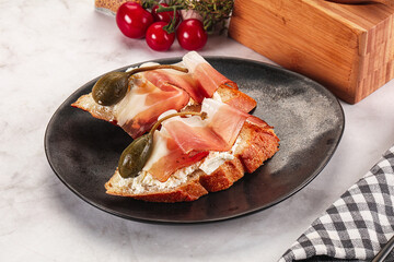 Bruschetta with jamon and caper berries
