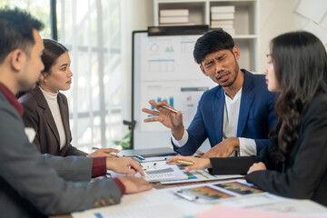 A group of people are sitting around a table with a white board behind them