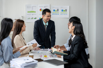 A group of people are sitting around a table with papers and books