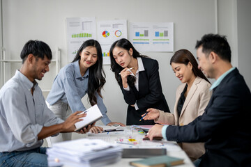 A group of people are sitting around a table with papers and graphs