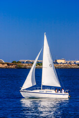 Fototapeta premium A white sailboat is sailing on a blue ocean