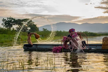 Fotobehang Lotusbloem An old man sits on an old wooden boat and picks lotus flowers. Men and children pick lotus flowers in swamps  © Yellow Boat