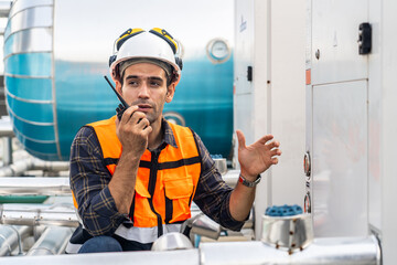 Male technical foreman in safety uniform inspects maintenance work talking on radio call with...
