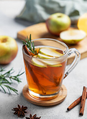 Homemade apple punch with apples, cinnamon and rosemary in a cup on a light  background