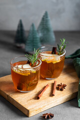 Homemade apple punch with fresh apples, cinnamon and rosemary in a two cups on a wooden board