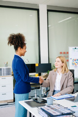 Two office colleagues discuss ideas for a startup project in a modern workspace, using laptops