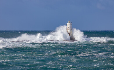 Ocean waves crashing against a lighthouse during a powerful storm at sea