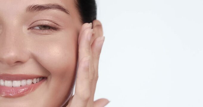 Close-up portrait of a cheerful woman gently touching her face, showcasing radiant, glowing skin. Perfect for luxury skincare campaigns, spa treatments, and cosmetic ads. 