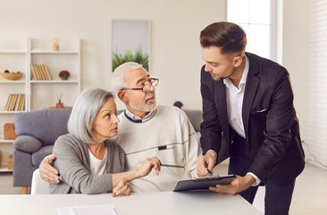 Senior family couple is engaged in a negotiation with a consultant and insurance agent during a meeting at home. Conversation focuses on investments and insurance for elderly clients.