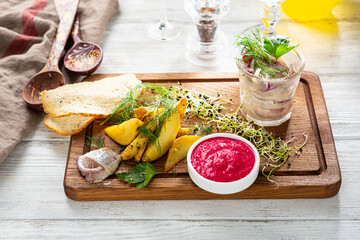 Roast Potatoes wedges with salted herring and horseradish sauce on wooden board