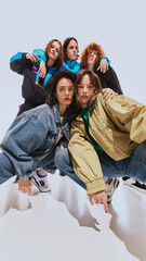 Nostalgic vibes. Five stylish young people in their 20s in iconic 90s fashion styles, Demin, windbreakers and oversized jackets, posing against white studio background. Concept of 90s fashion, youth