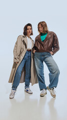 Full-length portrait of beautiful young women, blonde and brunette, wearing trench coat and leather...