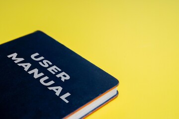 A close-up image of a user manual book on a bright yellow background. Guide, support, tutorial...