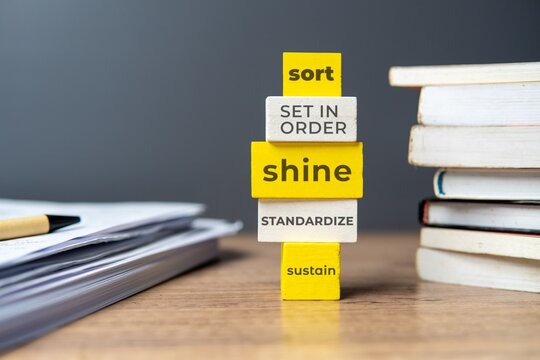 The 5s workplace organization method. Stack of wooden tiles with text SORT, SET IN ORDER, SHINE, STANDARDIZE and SUSTAIN.