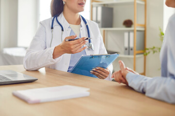 Cropped shot of physician or cardiologist sitting with clipboard, giving consultation to patient...