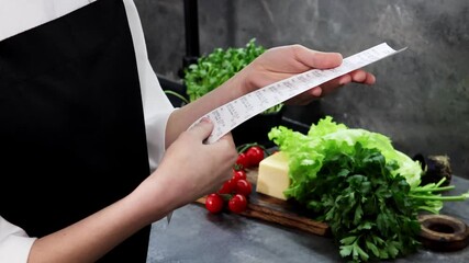 A chef reviews a long grocery list while surrounded by vibrant vegetables and herbs, preparing for an exciting cooking experience in a cozy kitchen filled with fresh produce.