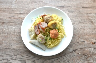 dry Chinese yellow egg noodles topping steamed Hakka meatball made from chop pork stuffing fried tofu and dumpling couple slice red barbecue pork on plate