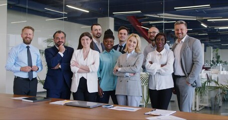 Happy smiling diverse business people men and women looking cheerful at camera and smiling indoors. Company employees or group of staff standing in office on meeting. 4k video. Slow motion video.