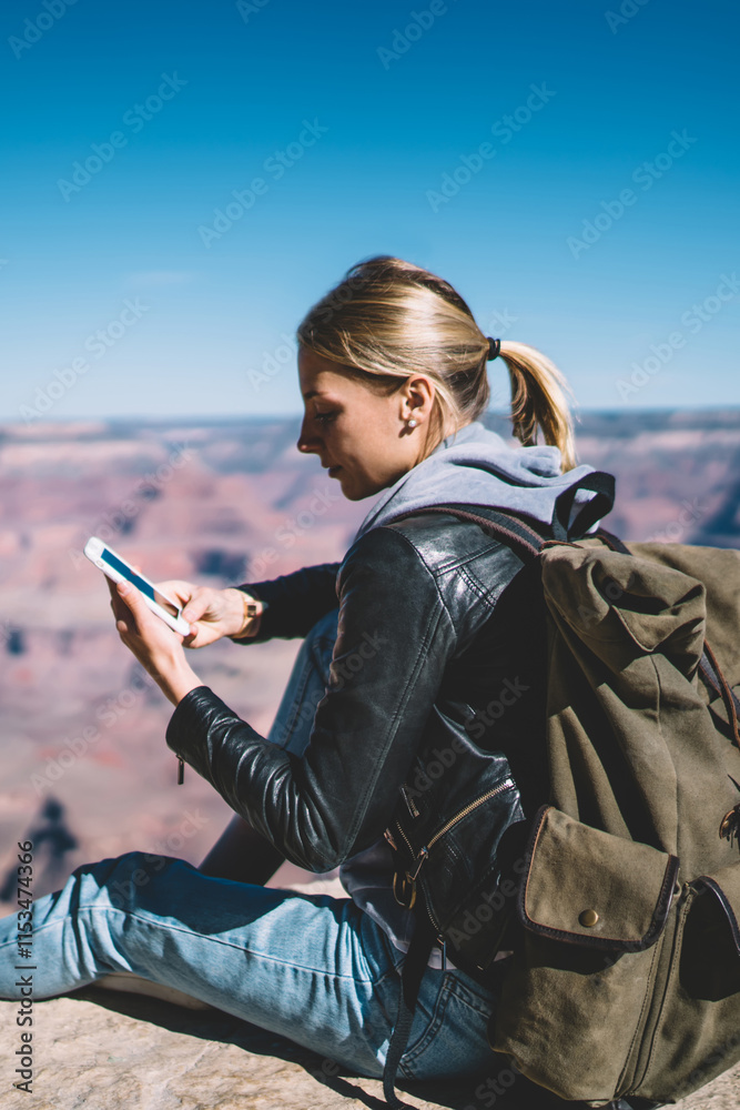 Wall mural young female tourist satisfied with mobile data network in mountains sending message on telephone re