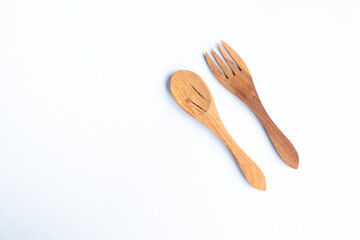 A pair of wooden spoons and forks are placed on a clean white surface