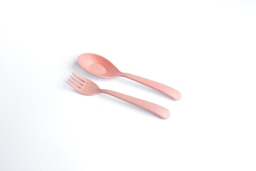 A pair of pink spoon and fork placed on a clean white surface
