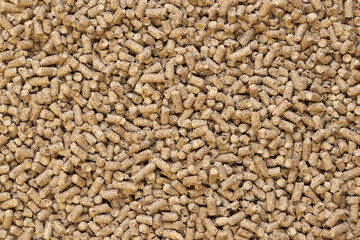 Wood pellet cat litter as background, closeup. Pressed wood, large granules. Pellets. A pile of wood granules. Texture. Wood filler for cat toilet, top view. Hygienic filler for pets