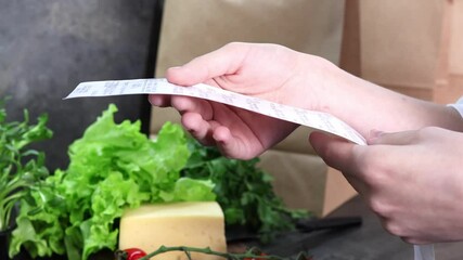 A skilled cook carefully examines a list of ingredients while surrounded by vibrant greens, fresh tomatoes, and cheese, capturing the essence of culinary inspiration in the kitchen.