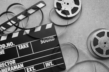 Movie clapper and film reels on grey textured table, flat lay