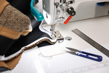 Sewing machine and other tools on white table in professional workshop, closeup