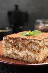Delicious tiramisu with mint on black wooden board, closeup