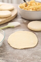 Making pirozhki (stuffed pastry pies). Pieces of dough on wooden table, closeup