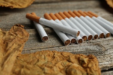 Dried tobacco leaves and cigarettes on wooden table, closeup © New Africa