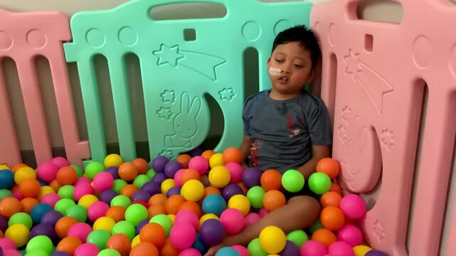 A child living with cerebral palsy is playing in a colorful ball pool in the occupational therapy room