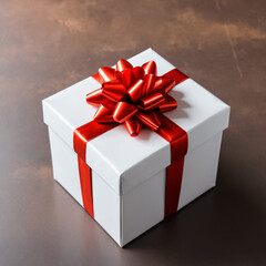 Fototapeta premium A white box tied with a red ribbon on a dark background. A bow made of red ribbon.