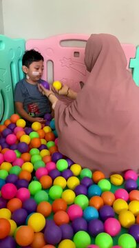 A child living with Cerebral palsy and wears a nasogastric tube or NGT on his nose is playing in a pool full of colorful balls