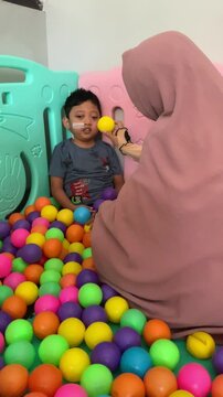 A child who lives with Cerebral palsy and wears a nasogastric tube or NGT on his nose is playing in a pool full of colorful balls