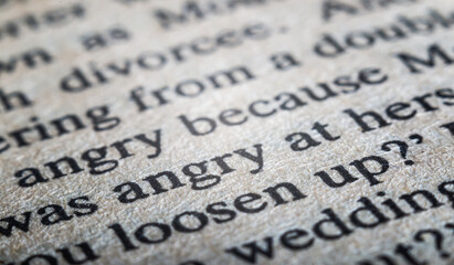 Macro photo of a page from a book that clearly shows the structure of the paper and the word "angry" in sharp focus.