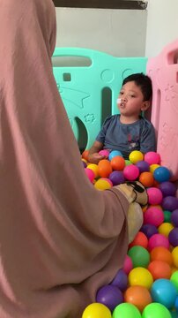A child who lives with Cerebral palsy and wears a nasogastric tube or NGT on his nose is playing in a pool full of colorful balls