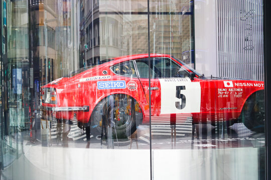 TOKYO, JAPAN - November 19, 2020: People view a 1972 Datsun Fairlady 240Z displayed on a revolving platform in the window of Ginza Place Nissan Crossing.
