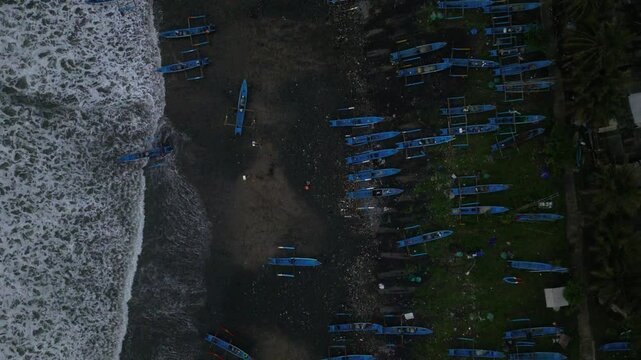 A lot of fishing boats moored on the beach of Pasir with foamy sea waves