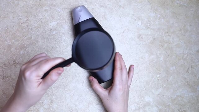 Female hands holding a can of shampoo, without any inscriptions or symbols. Open space for text on the surface of the package. Black and white plastic box from under the hygiene product