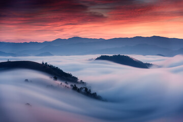 Sea of fog flowing on hill in countryside at sunrise